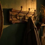 Porte manteau mural vintage en laiton patiné et bois, entrée verte à l’orée du jour.